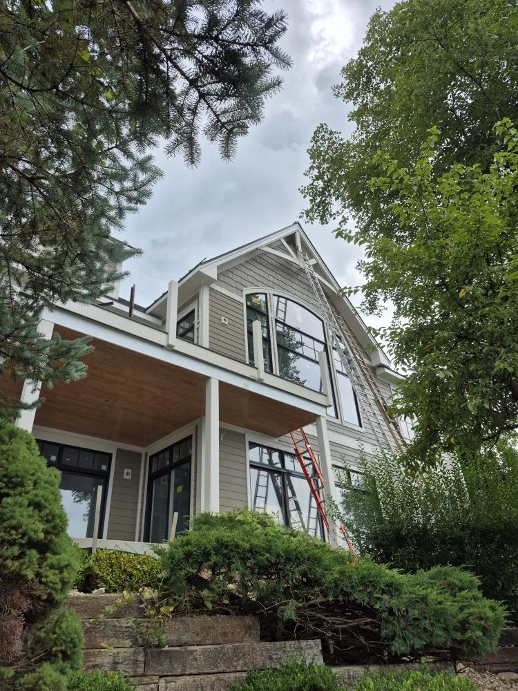 Craftsman home with a curved gable window, gray siding and white trim